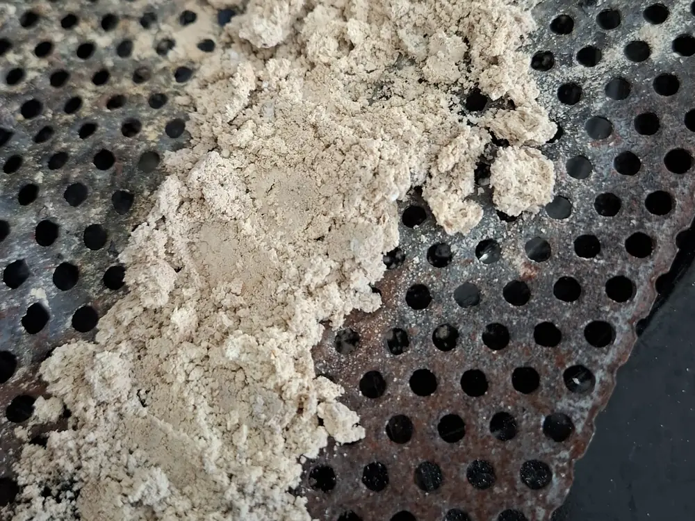 Pale grey ash residue left on the burner after a full burn cycle